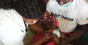 Cedric Kwaou holds his son as he receives his scheduled immunizations